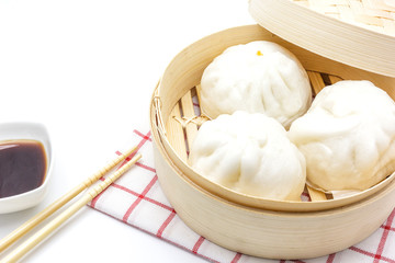 Fototapeta na wymiar Steamed pork buns (chinese dim sum) in bamboo basket, serve with chopsticks and napkin on a white background, Top view with copy space and text.