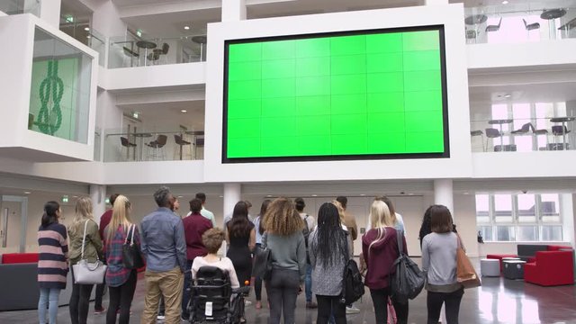 Students under big AV screen in university atrium, back view, shot on R3D