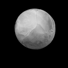 Round ice cube isolated on black.