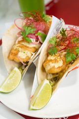 Golden fried cod fish taco served with parsley, red onion hollandaise sauce, and a fresh wedge of lime.