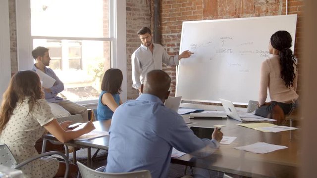 Businessman At Whiteboard In Office Giving Presentation 