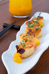 Delicious pan seared organic scallops, served with freshly sliced oranges. Presented professionally and shot with a shallow depth of field.