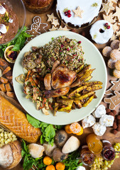 Unique beautiful christmas meal platter, with roast chicken and vegetables, surrounded by cakes, mince pies, fruit, bread and jam.