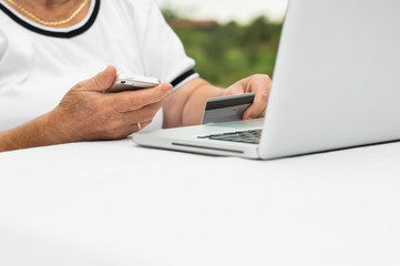 Old woman  doing her shopping online using a credit card and mobile phone