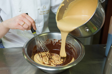 Creamy salted toffee sauce being mixed and blended, into a bowl of rich dark chocolate sauce.