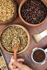Freshly ground coffee beans in a metal filter and coffee beans with brush for background