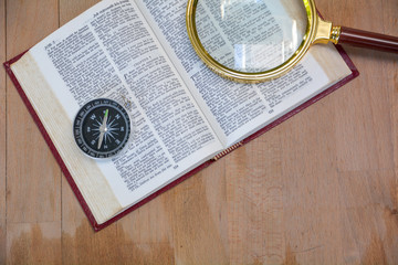 bible book and magnifying glass on wood background