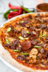 Spicy pepperoni, chicken and bacon pizza with jalapeno slices