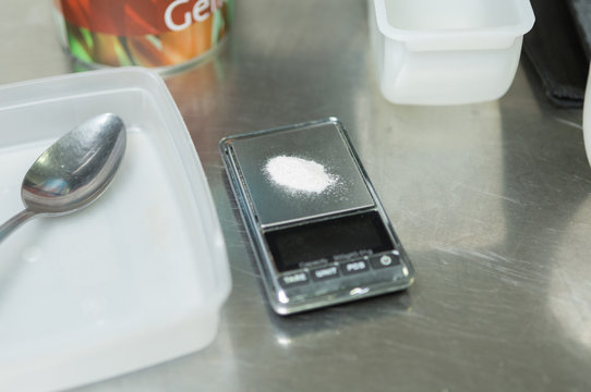 Salt on a digital measuring scale, surrounded by empty plastic containers with beautiful depth of field