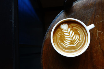 cup of latte art coffee on wooden background