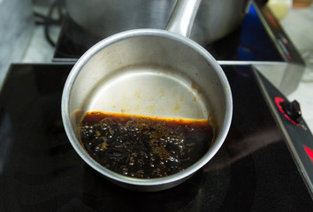 A hot pan of boiling coffee, on and industrial chefs heating stove, in a kitchen.