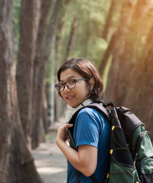 Asian glasses woman hiker with backpack and headphone smiling on nature background.