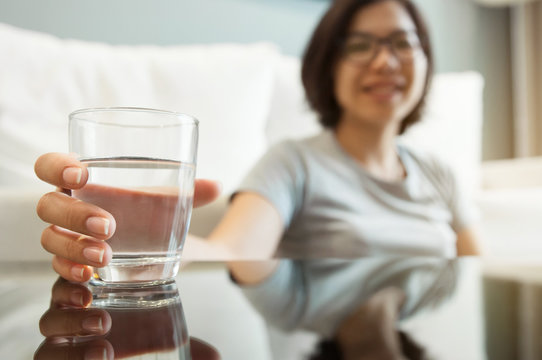 Asian glasses woman holding glass of water for drink. Woman smiling. Happiness, fresh.