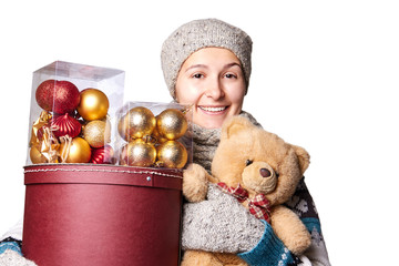 Young cute smiling girl in sweater, holding a box of Christmas decorations. Winter, Cristmastime, New Year holiday.