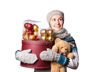 Young cute smiling girl in sweater, holding a box of Christmas decorations. Winter, Cristmastime, New Year holiday.