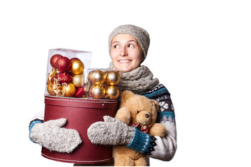 Young cute smiling girl in sweater, holding a box of Christmas decorations. Winter, Cristmastime, New Year holiday.