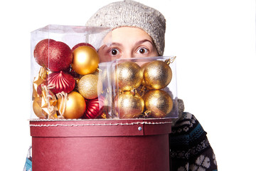 Young cute smiling girl in sweater, holding a box of Christmas decorations. Winter, Cristmastime, New Year holiday.