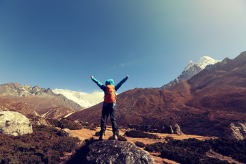 cheering young woman hiker open arms at the himalaya mountains