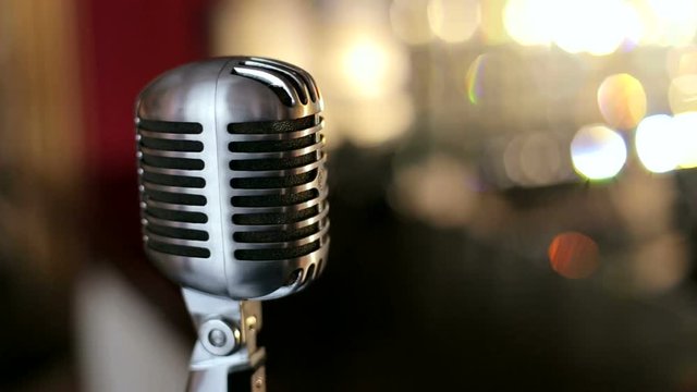 Vintage microphone in a karaoke bar. The microphone illuminated with bright light. Bokeh. Slow motion.