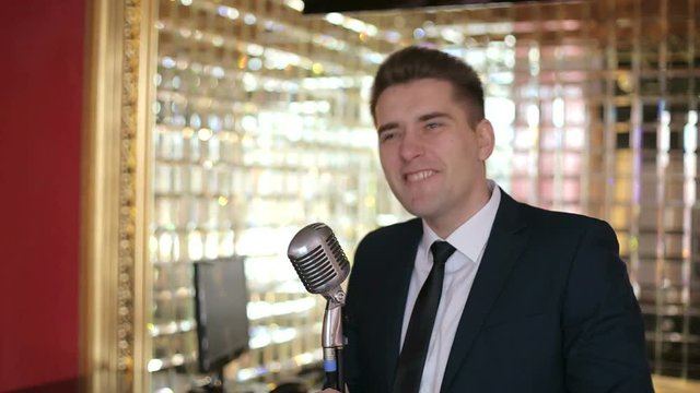 Elegant man speaking into a vintage microphone. Handsome man in suit singing over the retro microphone. 