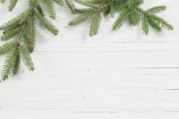 Christmas fir branches on white wooden background