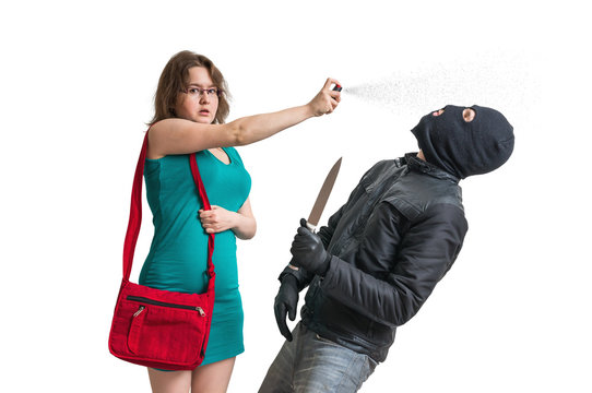 Young woman is defending with pepper spray against armed thief with knife. Isolated on white background.