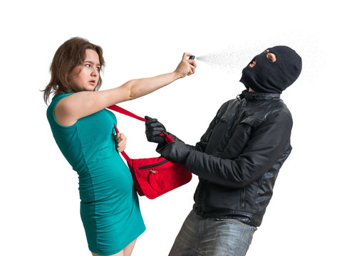 Self defense concept. Young woman is fighting with thief and using pepper spray. Isolated on white background.