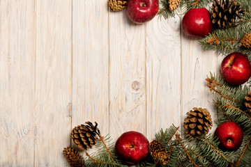 Christmas apples and spruce branches with cones on white wooden