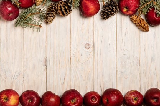 Christmas apples and spruce branches with cones on white wooden