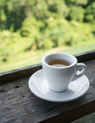 Cup of tea on wooden bar. Beauty nature background of mountains and tea plantation landscape at Doi-Montngo , Chiang Mai, Thailand