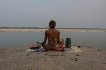 Indian yogi meditates on the bank of the Ganges