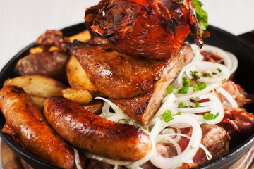 Assortment of grilled chicken and meat snacks close-up. Variety of fried sausages, wings and hams with onion rings. Junk food concept