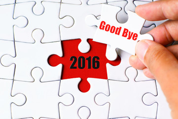 "2016" word on missing puzzle with a hand hold a piece of "Good Bye" word puzzle want to complete it - new year, complete and farewell concept