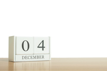 Closeup surface white wooden calendar with black 4 december word on blurred brown wood desk isolated on white background with copy space , selective focus at the calendar