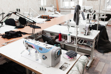 Interior of garment factory shop. Closes making atelier with several sewing machines. Tailoring industry, fashion designer workshop, industry concept