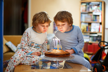 little kid boys twins celebrating birthday and blowing candles on cake