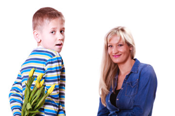 Little boy with mother hold flowers behind back.