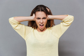 Angry stressed woman covering ears with palms and shouting
