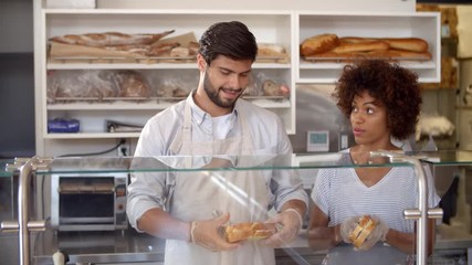 Manager training a woman behind the counter at sandwich bar