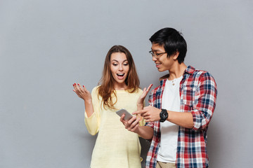 Portrait of a young excited couple with mobile phone