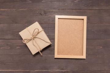 Gift box and picture frame are on the wooden background