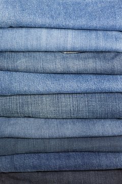 Stack Of Jeans Folded On White Background - Various shades of color.