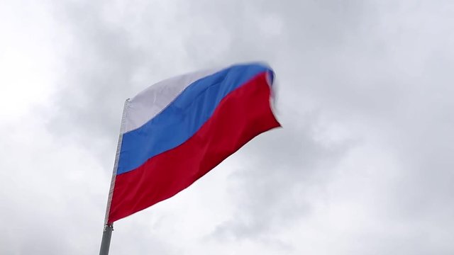 Russian flag flying in the background of blue sky with clouds