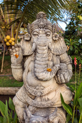 Stone Ganesha statue with flowers in the garden