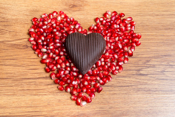Heart of red pomegranate seeds and dark chocolate - a declaration of love on Valentine's Day.
