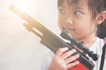 Asian child girl holding a gun filled with emotional commitment.