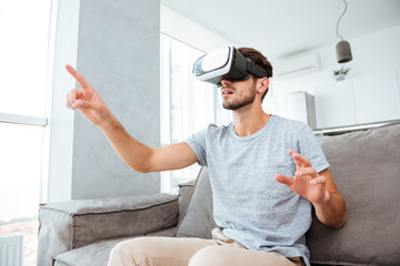Young man wearing virtual reality device and pointing