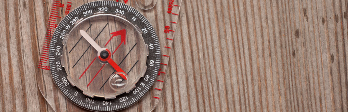 plastic compass over a wooden background - Powered by Adobe