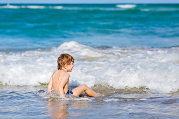 little blond kid boy having fun on ocean beach in Florida