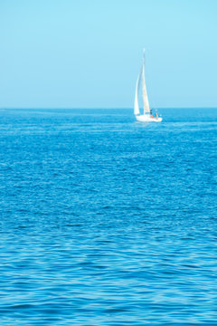 Blue summer seascape with distant yacht out of focus